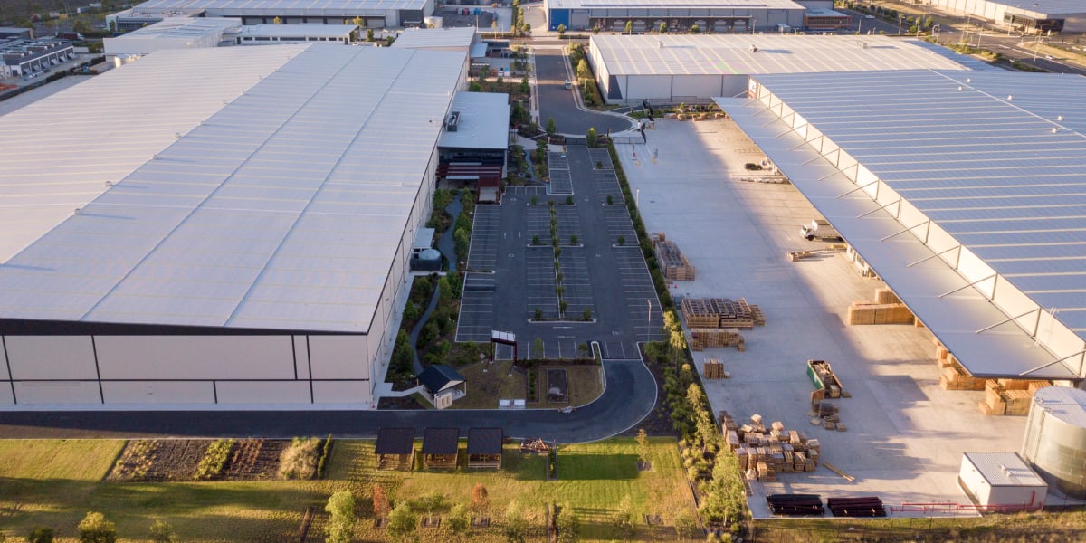 Aerial View Of Industrial Warehouse Complex With Parking Lot And Solar Panels