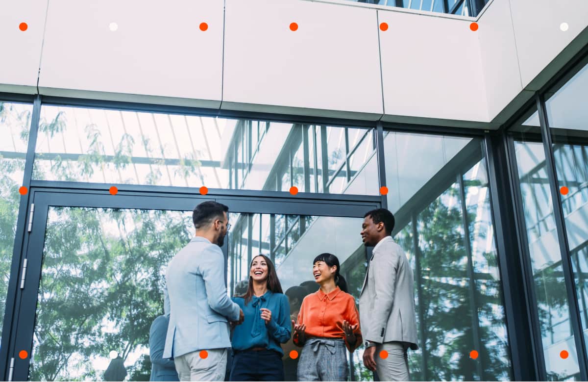 Four People Talking And Laughing In Modern Glass Office Building