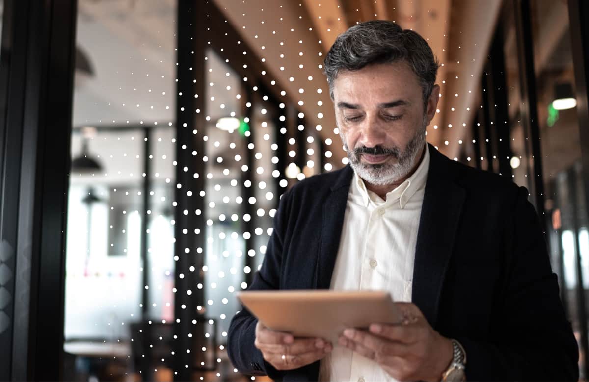 Man In Business Casual Attire Reviewing Tablet In Modern Lit Corridor