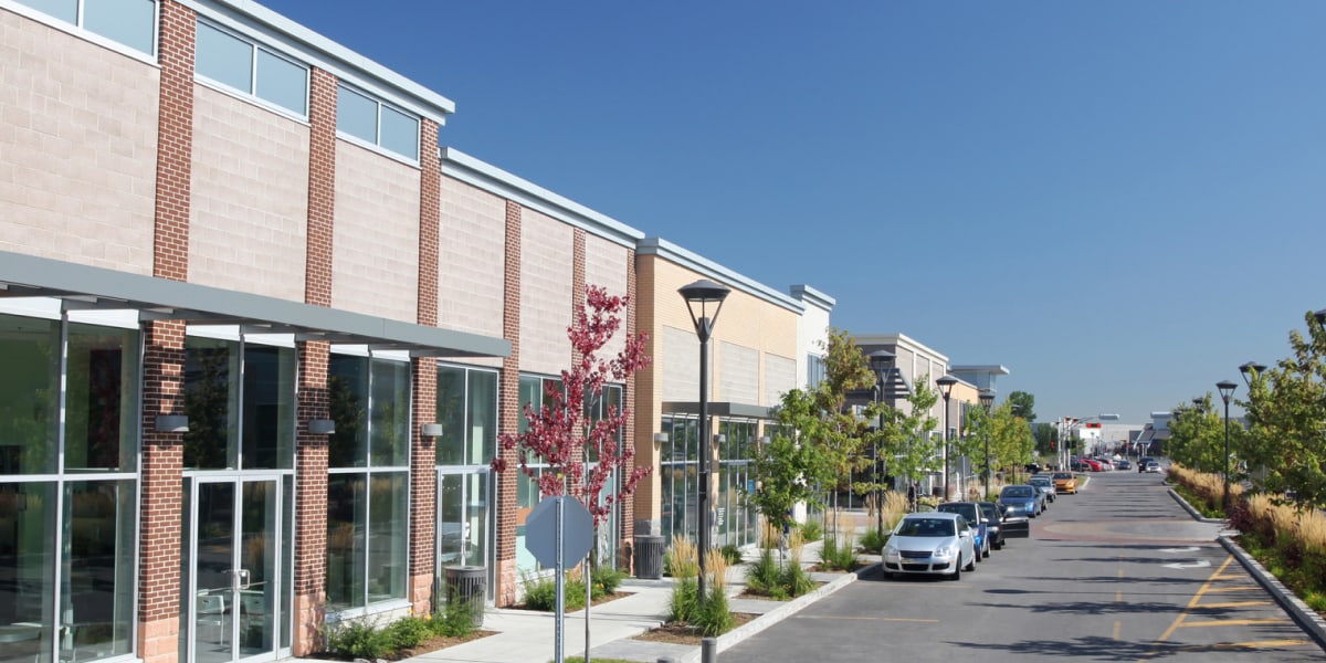 Modern Brick Commercial Building With Storefronts Along Tree Lined Street