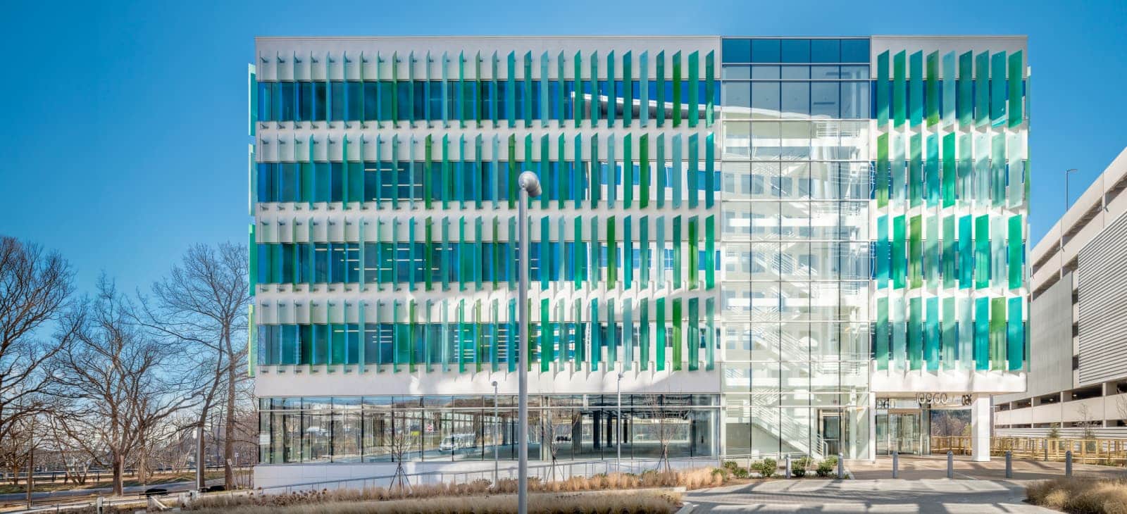 Modern Office Building With Green And Blue Vertical Louvers Glass Facade Hero