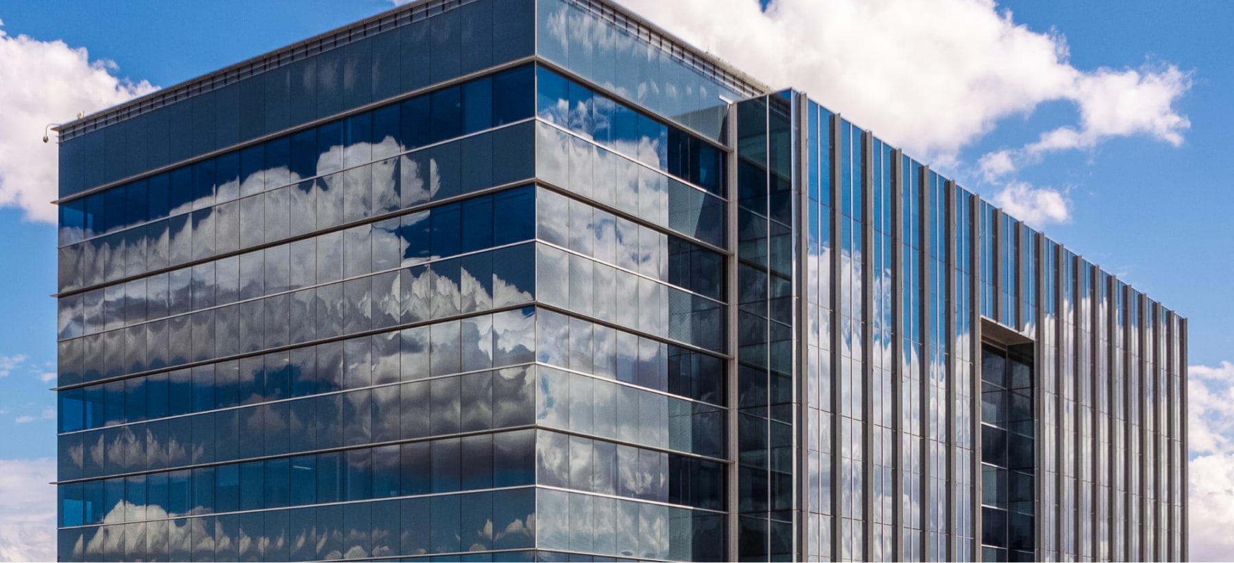 Modern multi-story office with reflective sides under blue sky