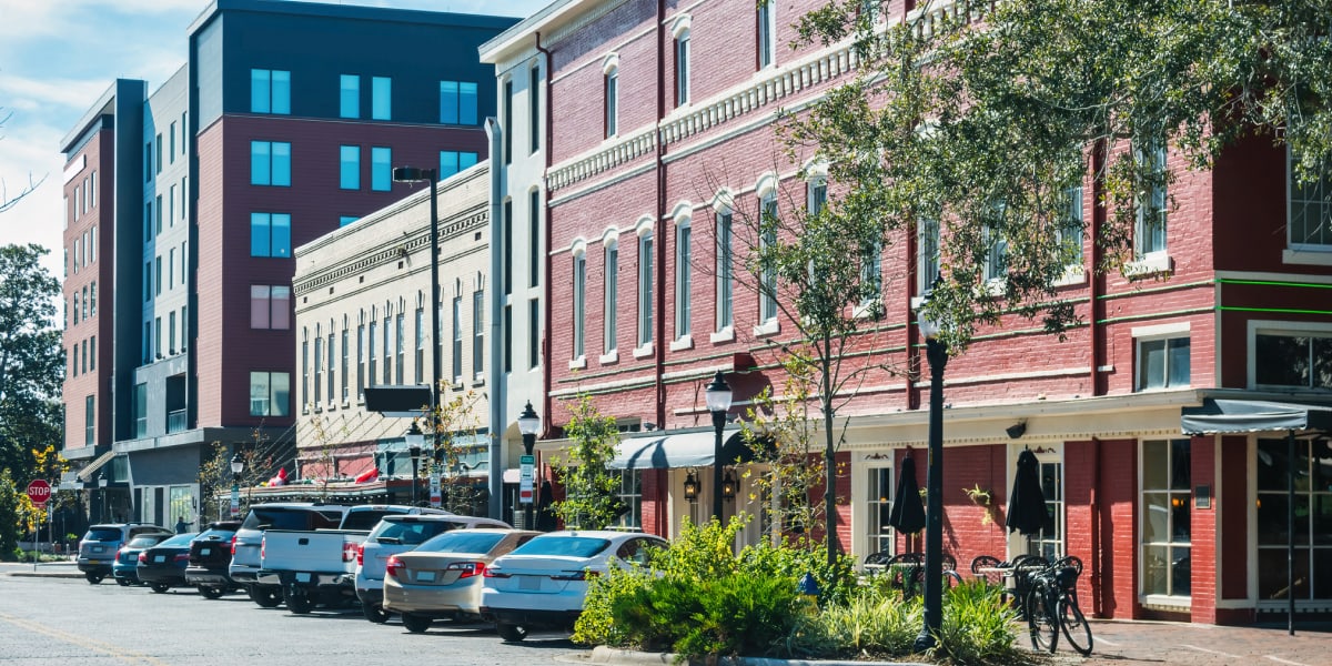 Row Of Parked Cars Along Brick Building Street With Storefronts And Ivy