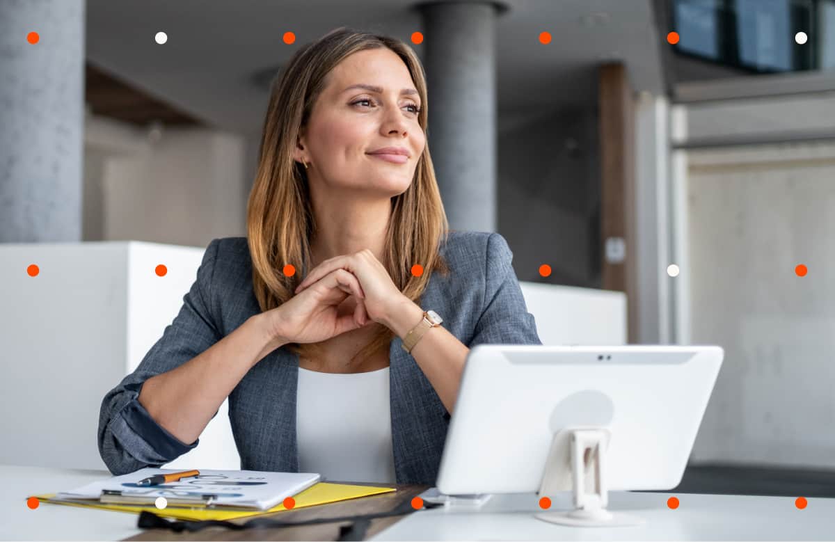 Woman In Business Blazer Looking Off Camera At Desk With Laptop