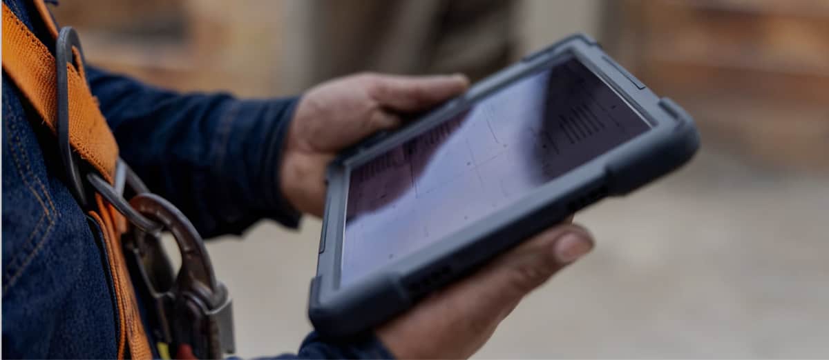 Worker Holding Rugged Tablet Device On Job Site